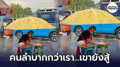 แม่ค้านั่งกางร่มอดทนขายขนมลูกชุบ หาเงินเลี้ยงชีพท่ามกลางฝนตกหนัก